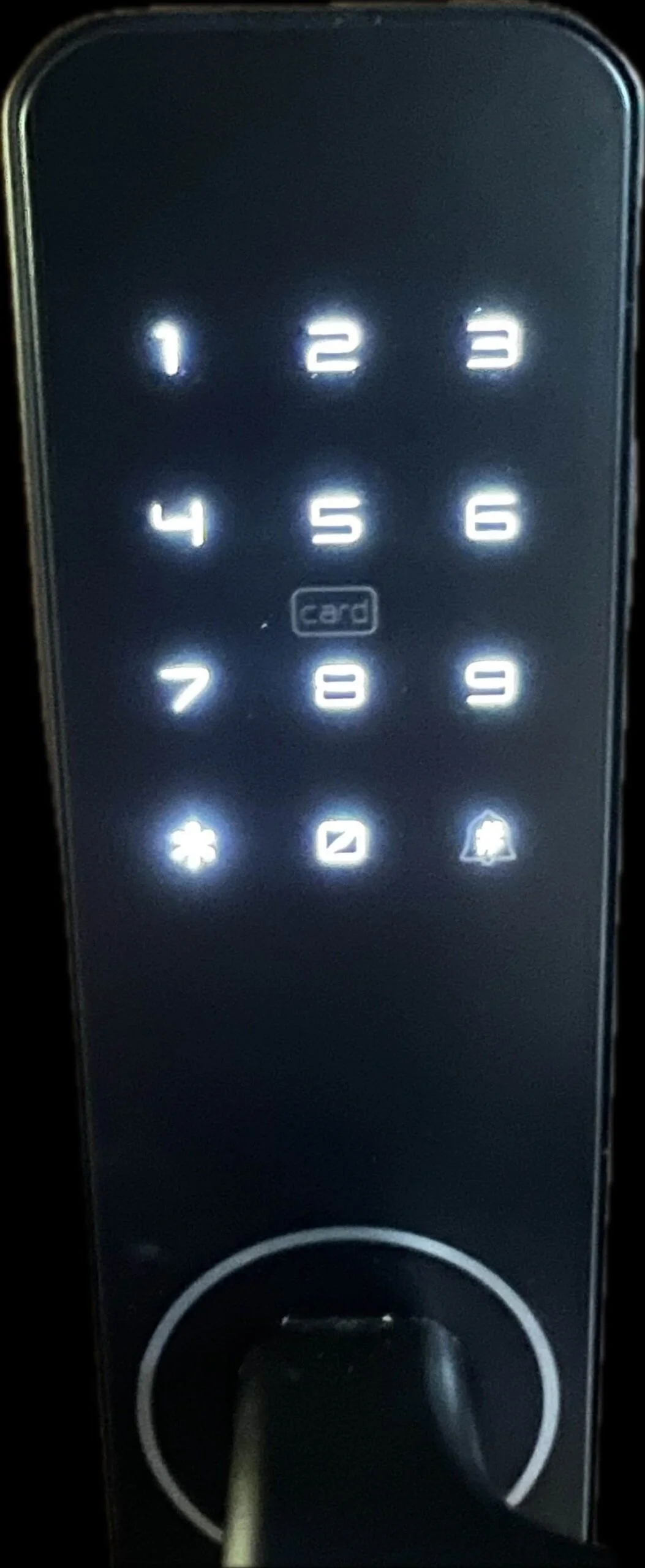 Nahaufnahme eines beleuchteten digitalen Tastenschlosses mit den weiß hinterleuchteten Zahlen 1 bis 9 und 0 in einem Raster sowie Symbolen für Karte, Sternchen und Glocke unter den Zahlen. Das Tastenfeld ist elegant und befindet sich auf einer schwarzen Griffplatte.